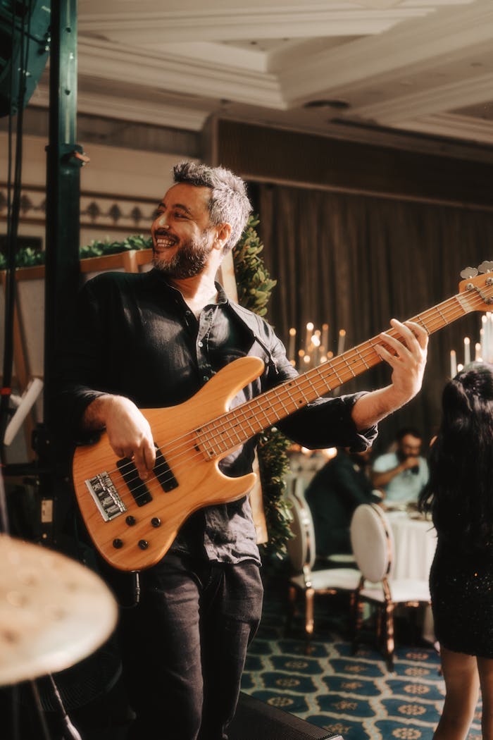 The Art of Drawing Readers In: Your attractive post title goes here Smiling bassist performing energetically at a lively indoor party setting, surrounded by elegant decor.