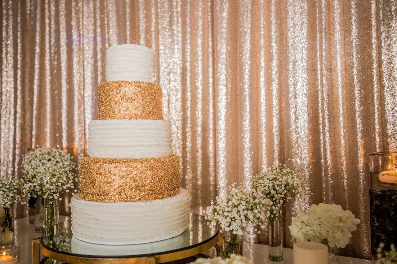 Luxurious four-tier wedding cake adorned with gold sparkle layers and surrounded by baby's breath flowers.