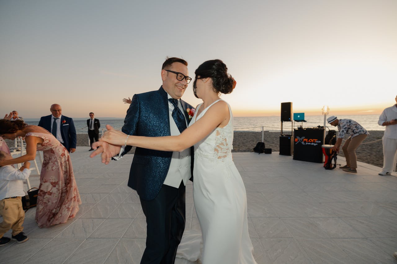 Mastering the First Impression: Your intriguing post title goes here A couple dances joyfully at their beachfront wedding reception during sunset.